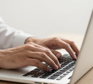 A close-up, high-quality photograph of a professional's hands typing on a high-end laptop in a bright, modern North American / US workspace. Soft off-white background with a focused, results-driven atmosphere and sleek tech aesthetic.