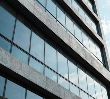 A professional photography shot of a modern architectural building in Jakarta with clean lines and large windows, reflecting a bright blue sky, conveying innovation and growth.