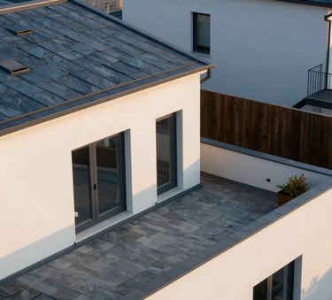 A sharp, high-angle photograph of a modern residential roof-terrace in a Western European / French suburb, featuring clean lines, slate blue and off-white textures, under soft morning light.