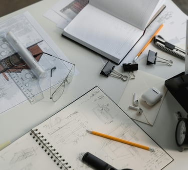 Carnet de croquis avec dessin de façade, plans d'architecte et lunettes sur un bureau en bois