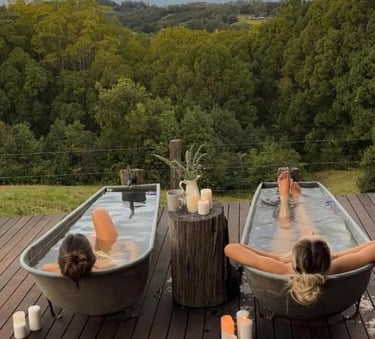 two ladies relaxation in an outdoor bath in nature at a wellness retreat by Luxe Wellness Spaces