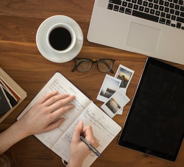 Brava Braun journaling in a notebook and a laptop