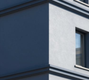 A close-up shot of a perfectly painted modern building facade with sharp lines and professional finish, showcasing dark blue #1E2A3A and light grey #F2F4F7 tones under natural daylight.