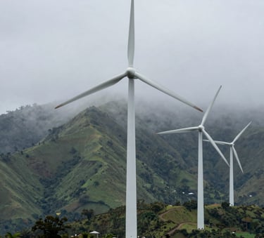 Sleek white wind turbines standing tall amidst a lush green mountain landscape in Latin America, morning mist, harmonious nature and clean industry photography.