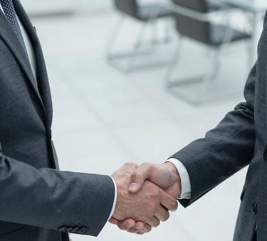 A close-up, high-angle shot of a professional handshake between two business leaders in suits. The background is a clean, modern corporate office with glass and steel elements. Lighting is bright and natural. The palette incorporates #1A202C and #F5F8FA for a professional, trustworthy feel.
