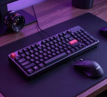 Sharp professional photography of a high-end mechanical keyboard and gaming mouse on a dark premium desk mat, North American / US workspace, moody violet lighting.