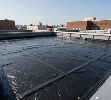 A wide-angle professional photograph of a modern commercial flat roof installation in New York City, featuring clean lines, structural steel gray components, and high-performance charcoal black waterproofing materials under bright North American daylight.