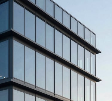 An architectural shot of a modern North American / International office building with steel blue grey steel and light powder blue glass panels reflecting a clear sky. Clean lines and minimalist design.