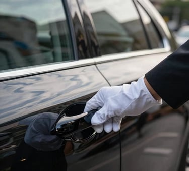 A close-up shot of a gloved hand opening the polished black door of a luxury executive sedan in a high-end district of a South American city. Soft white and dusty blue reflections on the car's surface, professional and sophisticated atmosphere.