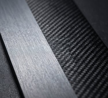 Macro photography of high-performance technical fabric and matte carbon fiber textures. Moody, dark lighting in a European design studio highlighting Steel Silver and Obsidian Black details.