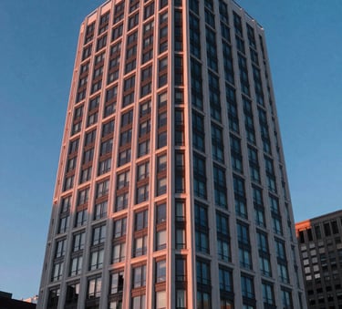 A sharp, modern photograph of an architectural landmark in a North American city, emphasizing clean lines and futuristic design. The sky is a deep blue, and the building reflects coral-tinted sunset light.