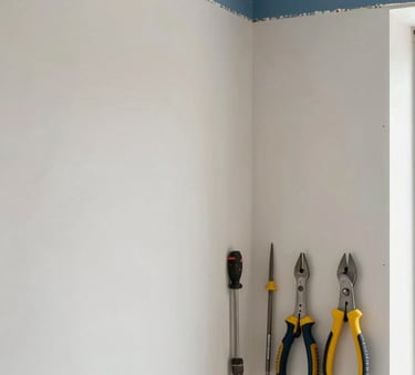 A high-detail photograph of a modern interior renovation project. The focus is on a perfectly finished corner with smooth walls in Pale Cloud White and Muted Steel Blue accents. Professional tools are neatly arranged in the corner, conveying precision and order.