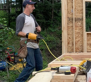 Image of Niko, a tall white male, holding a framing gun.