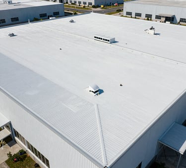 Aerial view of a perfectly installed white rubber roof on a large commercial building, clean lines, bright daylight, North American industrial park.