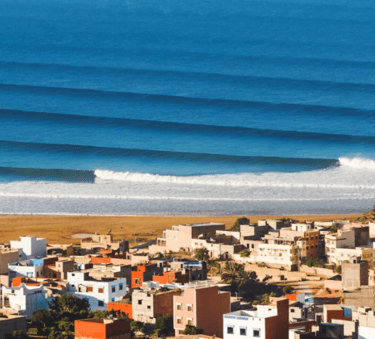a view of a beach with a surfboarder in the foreground
