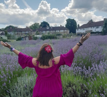 Image of the back of Sheila Cristina in a lavender field in London. In the distance is houses.