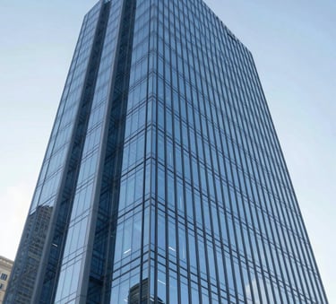 A low-angle shot of a modern, geometric glass skyscraper reflecting a clear sky, symbolizing high-level vision and corporate transparency. Incorporates shades of #3A506B and #8DA9C4. Sharp architectural lines, professional and sophisticated atmosphere.