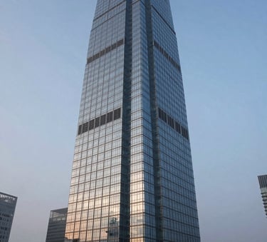A wide-angle, professional photograph of a modern glass skyscraper reflecting a soft misty blue sky at dawn, symbolizing global financial centers and institutional strength.