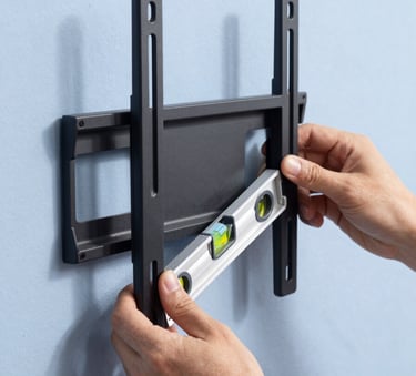 Close-up of a high-quality TV wall mount bracket being installed on a Pale Lavender Blue wall, a person's hands using a level tool, bright natural North American sunlight, professional photography.