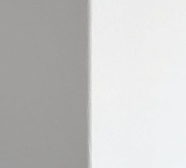 A close-up of a perfectly finished wall corner with smooth white texture, highlighting the meticulous attention to detail and craftsmanship. Natural, soft lighting with hints of #617488 and #B4C6D7 in the shadows to maintain brand consistency.
