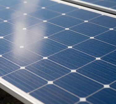 A close-up photograph of high-efficiency silicon solar cells reflecting a bright blue South American sky, capturing the modern textures and clean lines of sustainable technology in a professional setting.