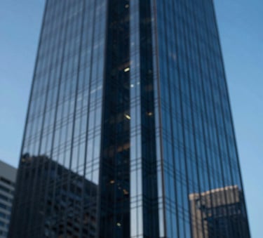 An abstract, high-contrast photograph of a modern glass skyscraper reflecting a clear blue sky, symbolizing corporate transparency and high-reaching financial goals. Deep #0A2A44 navy tones in the shadows.