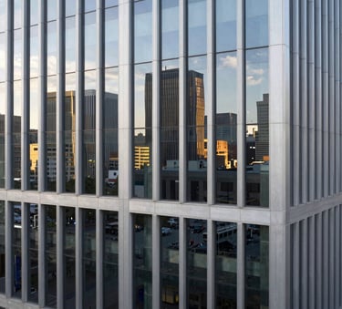 A high-angle architectural photograph of a modern corporate building facade with clean glass lines reflecting a North American city skyline, minimalist composition, bright daylight.