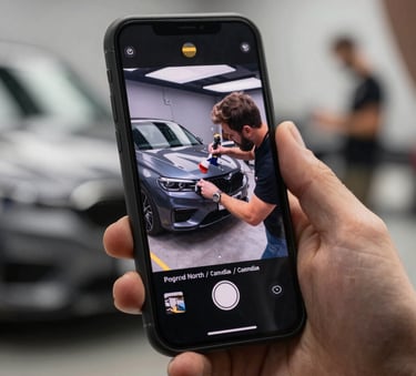 A close-up shot of a smartphone screen showing a viral video of a car detailing process, held by a person in a modern North American / Canadian setting.