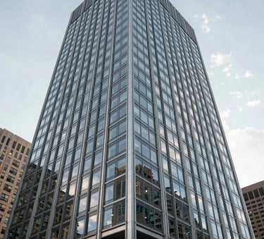 A sharp, low-angle architectural photograph of a modern glass and steel skyscraper in a North American city center, reflecting a clear sky with light gray and muted blue tones, symbolizing stability and corporate growth.