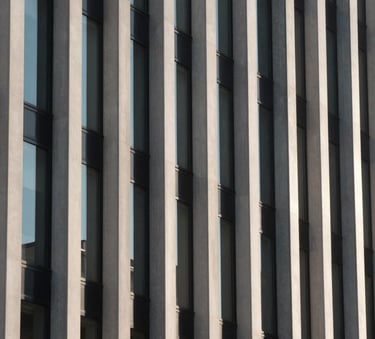 A close-up of a minimalist facade with clean vertical lines and glass windows, captured in the soft morning light of a North American urban environment, highlighting architectural precision in charcoal and off-white.
