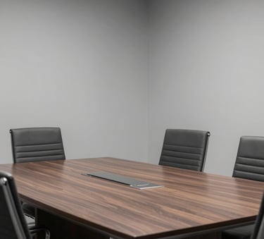 Interior shot of a modern, empty conference room with a large dark wood table and ergonomic chairs, soft gray walls, high-end North American corporate interior design.
