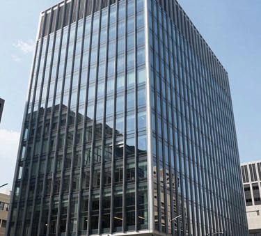A clean and modern architectural photography shot of a sleek glass-fronted office building in a North American / US city, with crisp shadows and bright daylight.