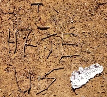 the words I hate us written in sticks on a brown gravel ground