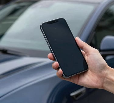 A professional close-up of a high-end smartphone being used to photograph a sleek modern car in an Oceanian urban setting, soft daylight, navy blue reflections.