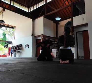 Adeline en kimono sur le tatami à Ubud, écoutant les explications de son professeur de Jiu-Jitsu bré