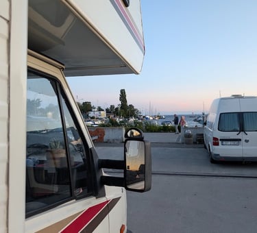 Casa Mariposa parked by the harbor at sunset with boats in the background