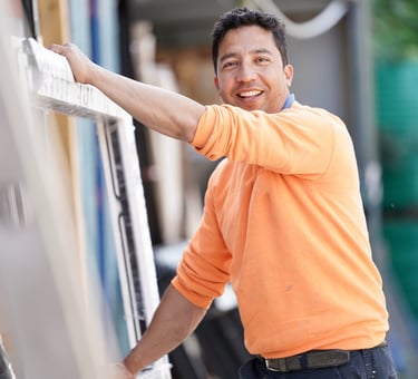 Window installer in orange shirt holding a uPVC window sill