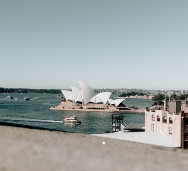 a view of a large building with a boat in the water. Opera House Sydney 