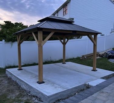 A recently-assembled wooden gazebo with a two-tiered metal roof.