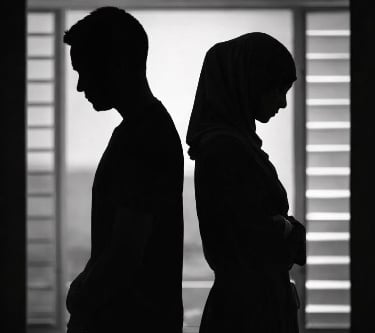 Silhouette of a sad couple standing back to back representing relationship conflict and divorce.
