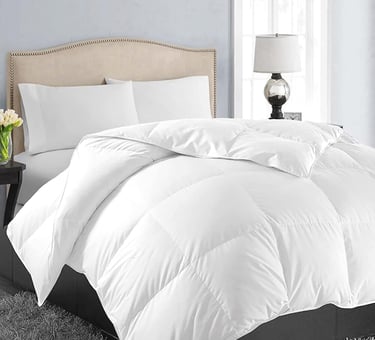 White plush down alternative comforter on a bed with a beige tufted headboard and white pillows.