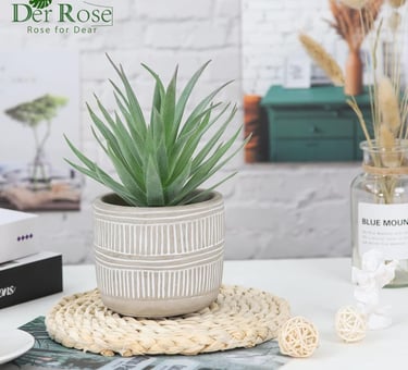 Small artificial succulent plant in a grey geometric pot on a woven coaster for home office decor.