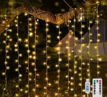 Warm white hanging curtain fairy lights draped from a tree branch in a garden with remote control.