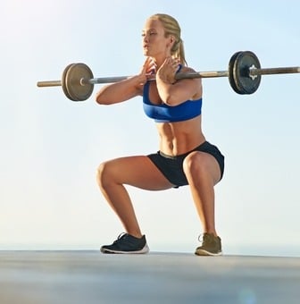 a woman doing squats with a barbell