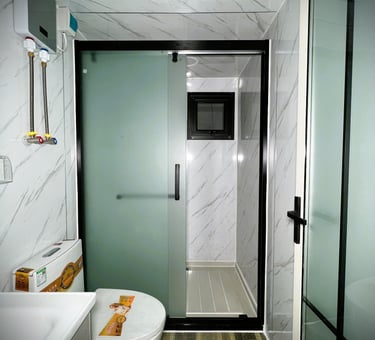 Modern small bathroom interior featuring a frosted glass sliding shower door and marble-patterned walls.