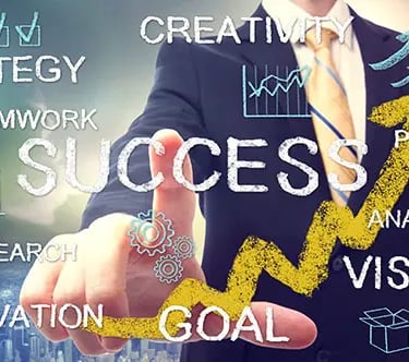 A person in a suit points to the word "SUCCESS" on a digital screen with words vision, innovation, research, strategy