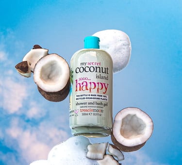 Treaclemoon Coconut Island shower gel styled with coconuts and foam against a blue sky