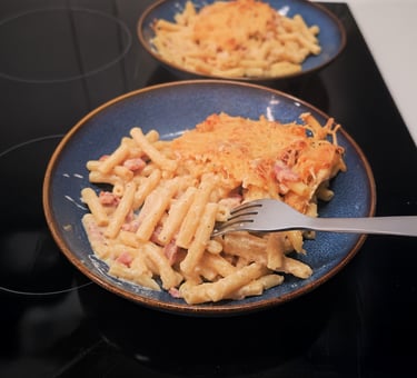 Gratin de macaronis dorés à l'emmental et lardons, nappe de sauce onctueuse au comté dans un plat