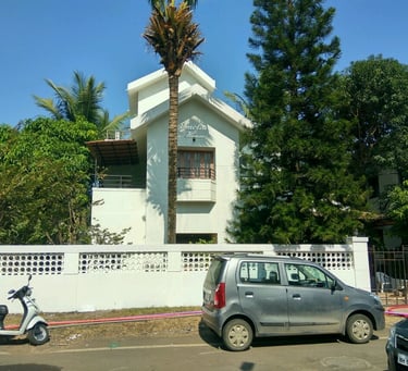 Completed exterior painting project: white house with palm tree in Pune”