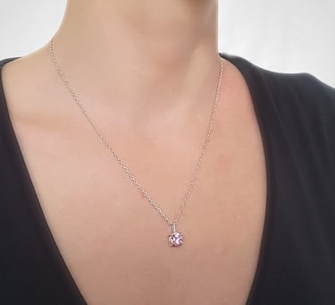 a woman wearing a black top and a necklace with a pink heart